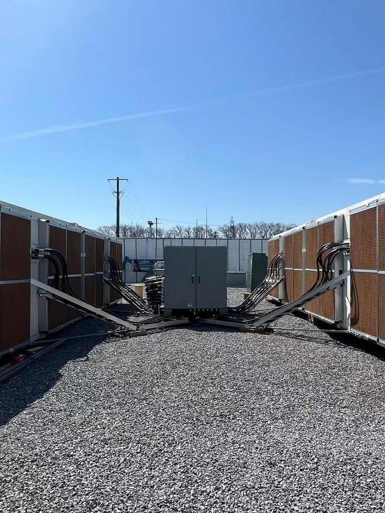 Containerized compute hall with evaporative cooling walls and heavy power cabling routed into a central switchgear cabinet.
